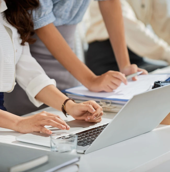 Equipo revisando datos y documentos en una reunión de trabajo con un portátil Equipo revisando datos y documentos en una reunión de trabajo con un portátil