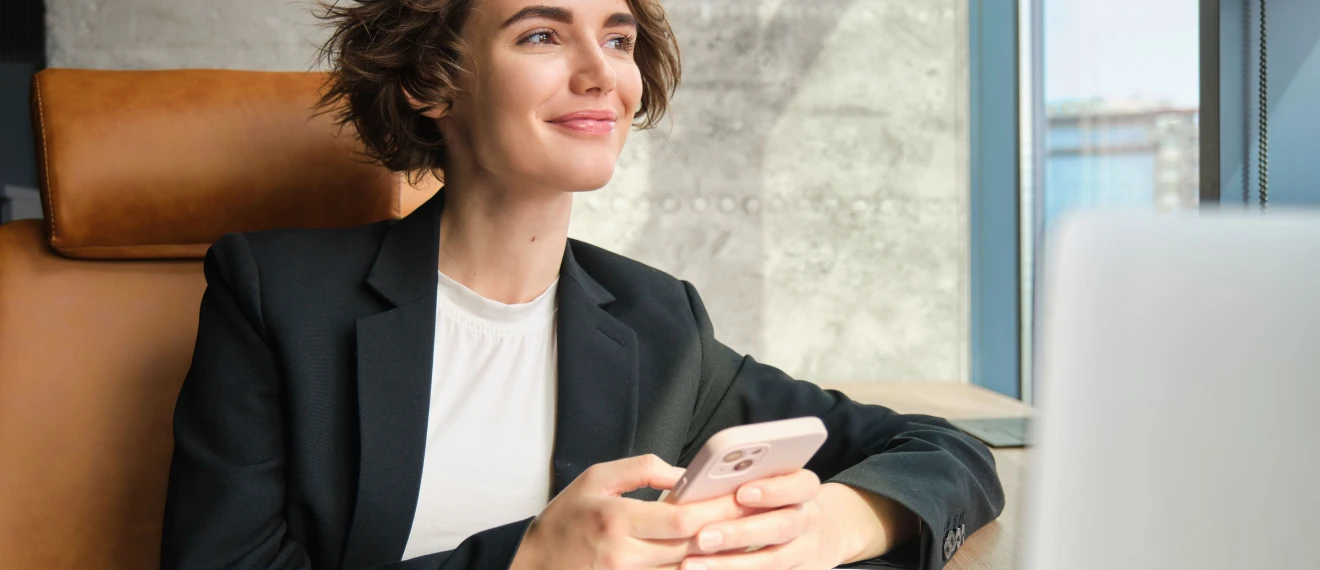 Asesora financiera revisando documentación en su oficina con su móvil
