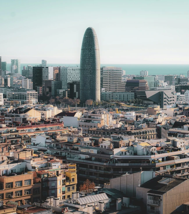 Vista panorámica de la ciudad de Barcelona con la Torre Agbar destacando entre los edificios y el mar de fondo Vista panorámica de la ciudad de Barcelona con la Torre Agbar destacando entre los edificios y el mar de fondo