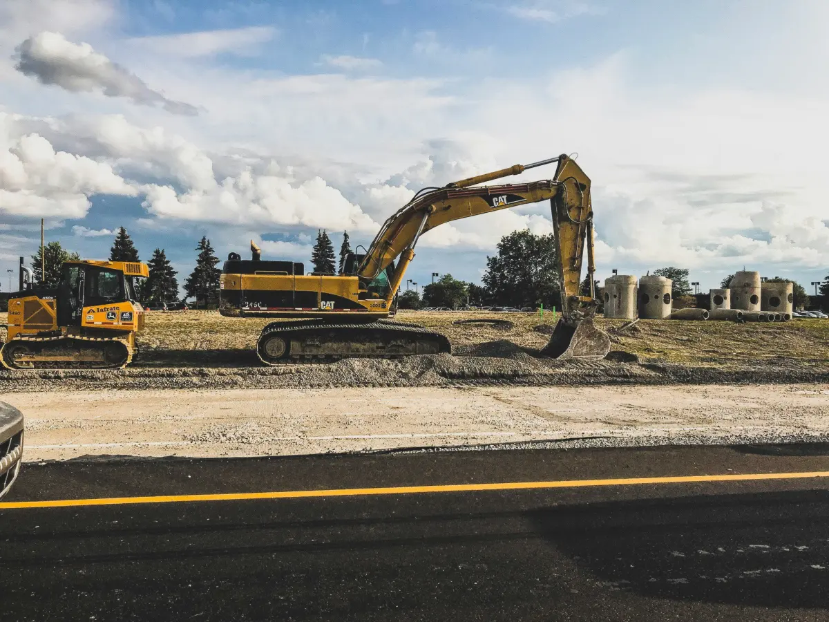 Excavadora y maquinaria de obra trabajando junto a una carretera