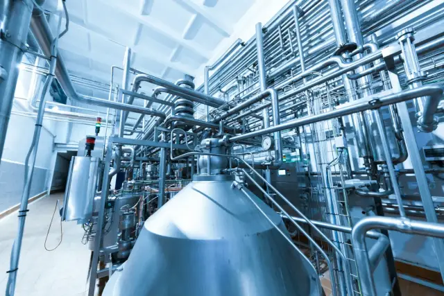Interior de una planta industrial con depósitos y tuberías de acero inoxidable