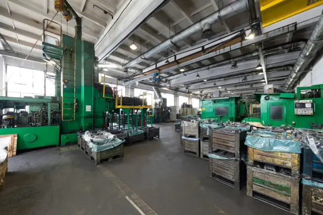 Nave industrial con maquinaria verde y cajas de piezas apiladas en el suelo