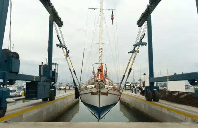 Velero suspendido por dos grúas elevadoras en un puerto deportivo
