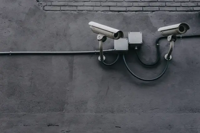 Dos cámaras de videovigilancia instaladas en una pared de cemento oscuro