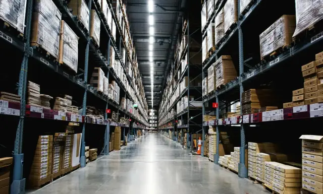 Almacén con altas estanterías metálicas y cajas apiladas en pasillos largos