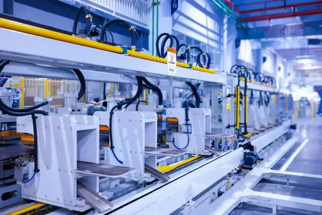 Línea de producción industrial con equipos blancos y cables en una fábrica