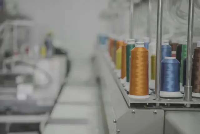 Bobinas de hilo de colores montadas en una máquina textil