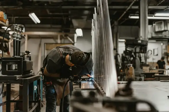 Operario trabajando con una máquina en un taller de componentes metálicos