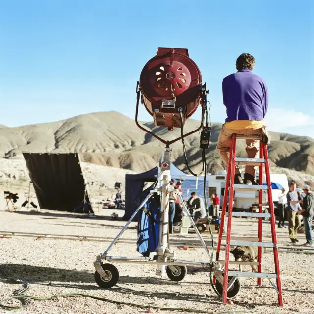 Rodaje en el desierto con foco de cine y un técnico subido a una escalera