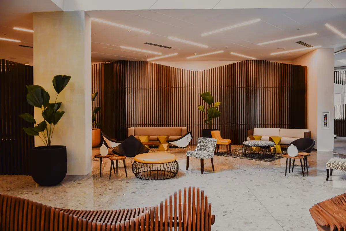 Vestíbulo de un hotel con zona de estar, butacas y plantas